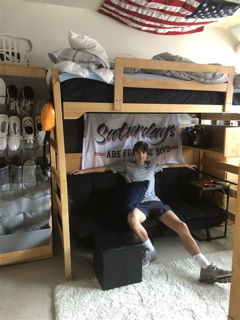 A Man Sitting On Top Of A Bunk Bed In A Room Filled With Sports Memorabilia