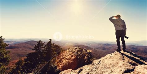 Man With A Camera Standing On At The Edge Of A Cliff Overlooking The