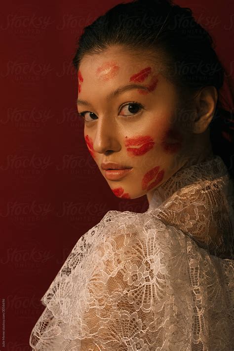 A Portrait Of An Asian Girl In A Lace Blouse With A Face Covered With Kisses By Stocksy