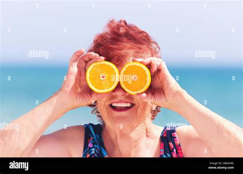 Funny Portrait Of Mature Woman Grandma Having Fun With Orange Eyes On Summer Vacation Stock
