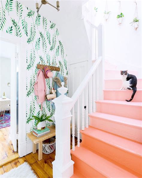 A Cat Is Sitting On The Stairs In Front Of A Wallpapered Hallway With