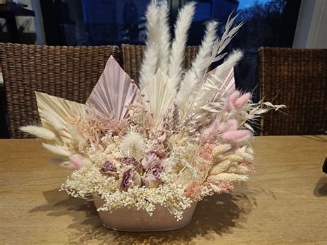 A Vase Filled With Lots Of White And Pink Flowers On Top Of A Wooden Table