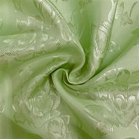 a close up view of a green fabric with white flowers and leaves on the side