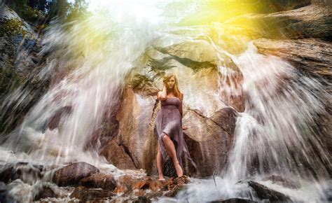 free photo woman in gray strapless long dress standing under waterfalls barefoot river wet