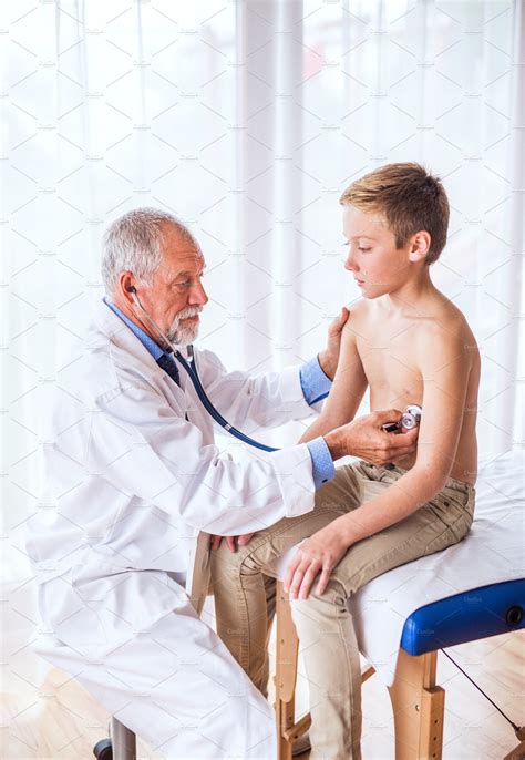 Senior Doctor Examining A Small Boy In His Office People Photos
