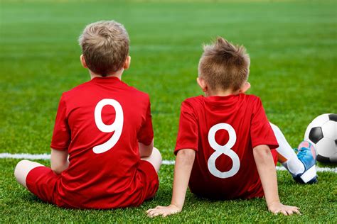 Young Football Players Young Soccer Team Sitting On Grass Boys In Red