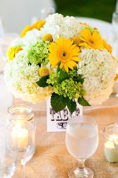 A Vase Filled With Yellow And White Flowers On Top Of A Table Next To