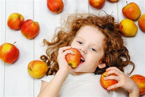 Happy Little Girl With Red Apples On Light Wooden Floor Top Vie Stock