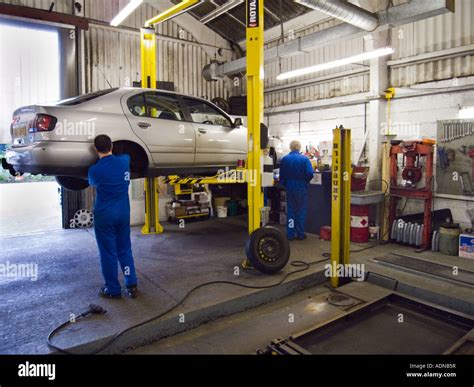 2 Car Mechanics Working In A Repair Garage With Hydraulic Car Lift