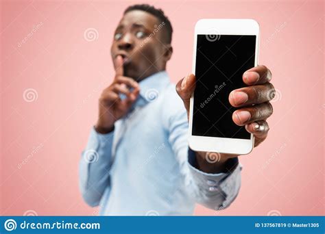 Indoor Portrait Of Attractive Young Black Man Holding Blank Smartphone