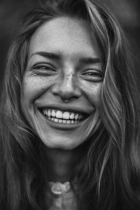 a smiling woman with freckles on her face and long hair is looking at the camera