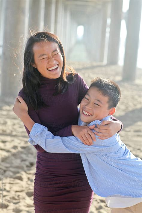 Asian Brother And Sister Hugging And Laughing At Beach By Stocksy