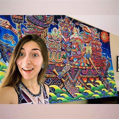 A Woman Standing In Front Of A Colorful Wall Hanging On A Wall Next To