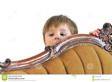 The Small Child Hides Behind A Sofa And Looks Out Stock Image - Image ...