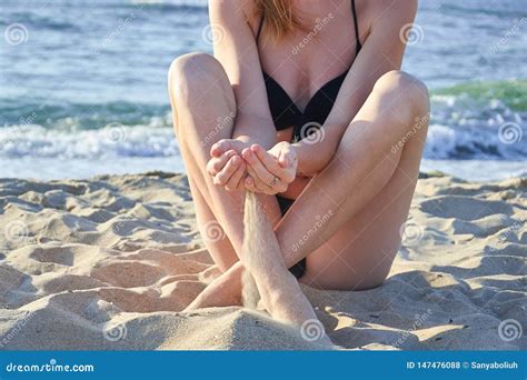 Beautiful Woman Sitting On The Beach Typing Sand In Her Hands On Sea Background Stock Photo
