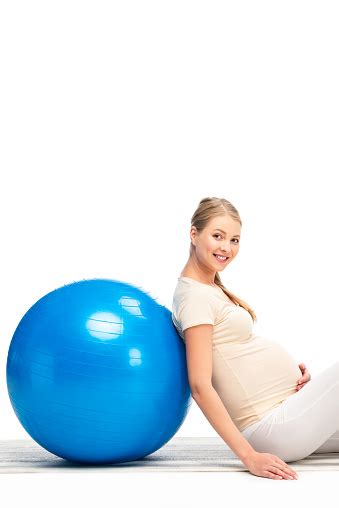 pregnant blonde woman leaning on blue fitness ball isolated on white