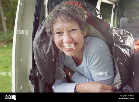 Portrait Of Senior Woman Inside Sleeping Bag In Open Camper Van Stock