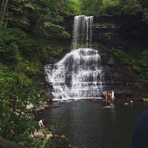 People Are Standing In The Water Near A Waterfall