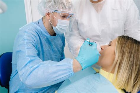 A Female Patient In Dental Glasses Treats Teeth At The Dentist With