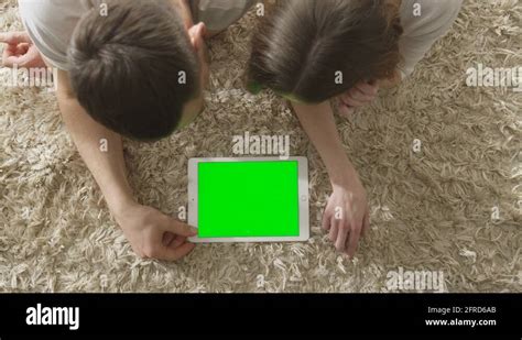Mockup Of People Laying On Floor And Using Tablet With Green Screen