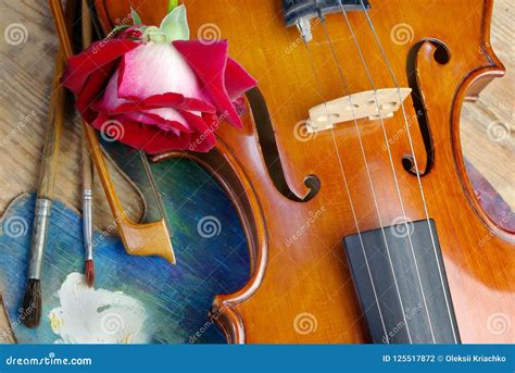 Violin Brushes Rose And Palette On A Wooden Background Top View