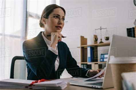 Female Lawyer In Eyeglasses At Workplace With Documents And Laptop In