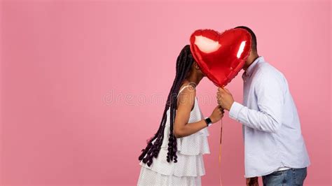 Romantic Black Couple Kissing Hiding Behind Red Heart Balloon Stock