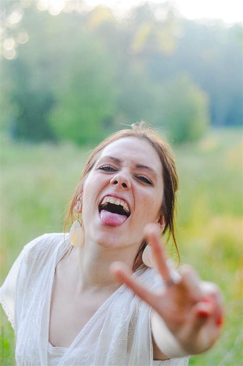 A Young Woman Making A Peace Sign And A Funny Face For The Camera By