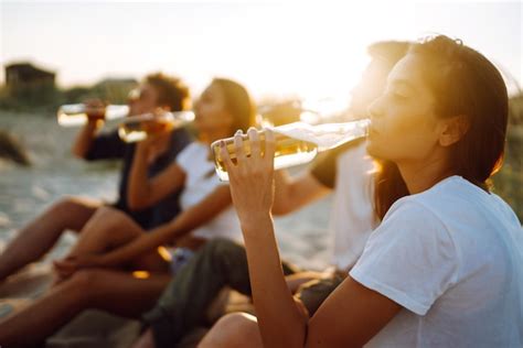 Premium Photo Young People Sitting Together At Beach Drinking Beer