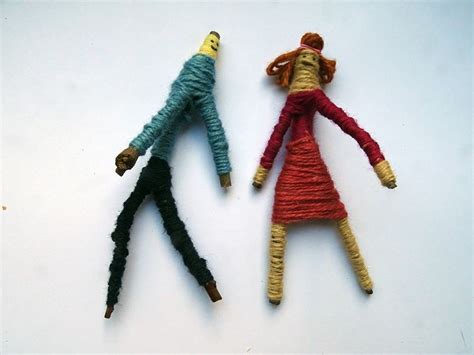 Two Dolls Made Out Of Yarn Sitting Next To Each Other