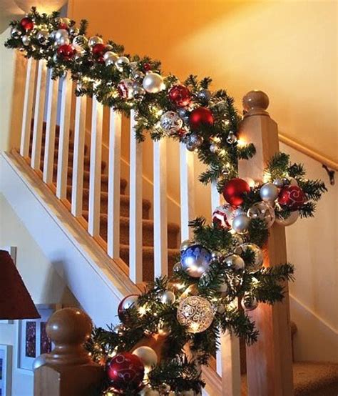 Greenery and stockings hung on staircase with red wrapped presents. Christmas Staircase Decorating Ideas - Pink Lover