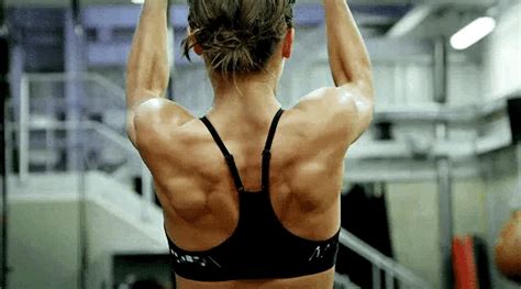 the back of a woman in a black sports bra top doing exercises on a gym floor