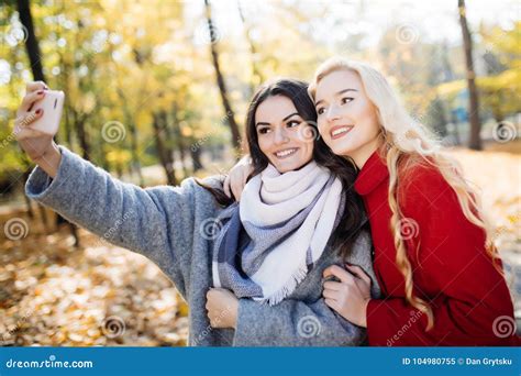 Two Happy Teenage Girls Taking A Selfie On Smartphone Outdoors In Autumn In Park Stock Image