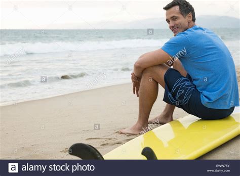 Portrait Smiling Man Sitting On Surfboard On Beach Stock Photo Alamy