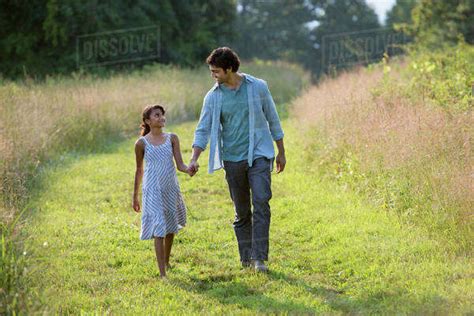 A Man And A Young Girl Walking Down A Mown Path In The Long Grass