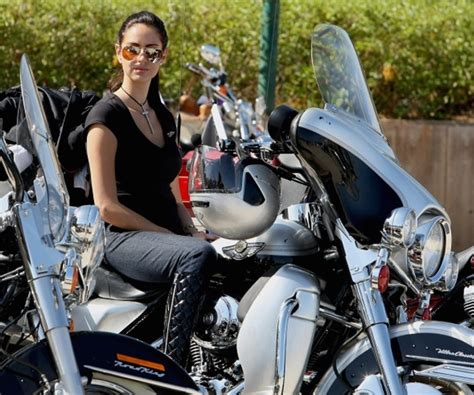 a photograph featuring a beautiful female motorcycle rider with her harley davidson as she