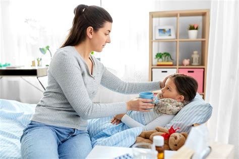 Mother Giving Tea To Sick Daughter Lying In Bed Stock Image Image Of