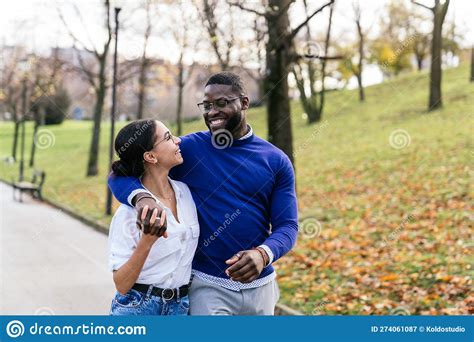 Joyful Interracial Couple Embraces In A Park At Sunset Amidst Fallen Leaves Exuding Pure