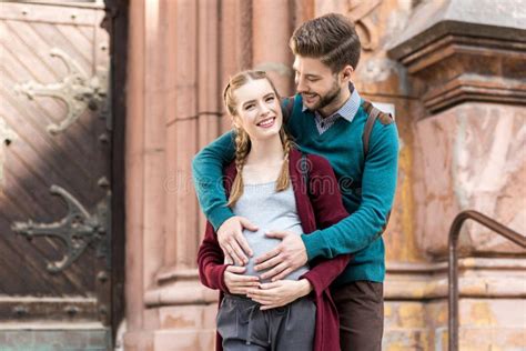 Young Man Touching Belly Of Pregnant Wife While Standing Stock Image