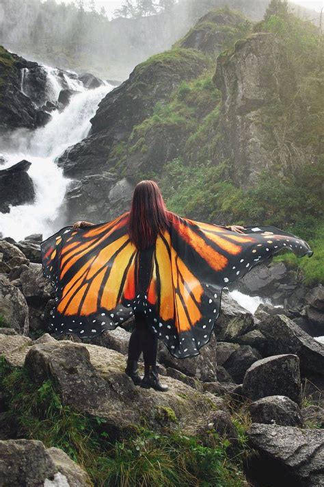 A Woman With A Butterfly Wings Standing On Rocks In Front Of A