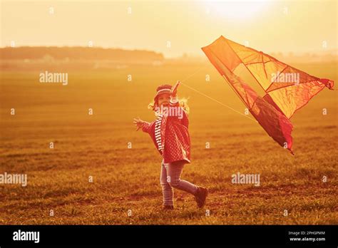 Happy Little Girl Running With Kite In Hands On The Beautiful Field At