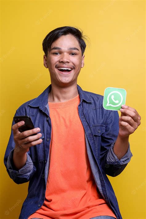 Premium Photo Young Man Holding Whatsapp Logo Picture And Smartphone
