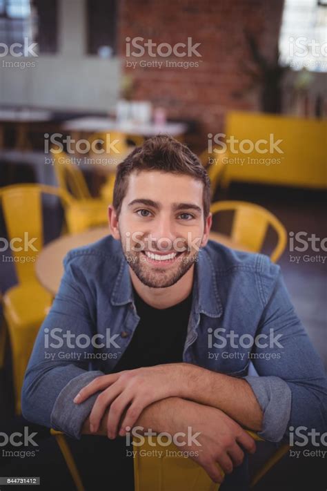 Portrait Of Smiling Handsome Man Sitting On Chair Stock Photo