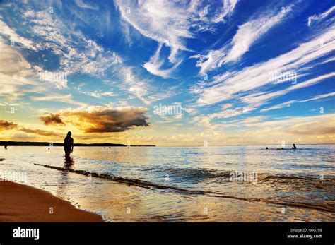 Woman Standing In Calm Ocean Under Dramatic Sunset Sky Summertime
