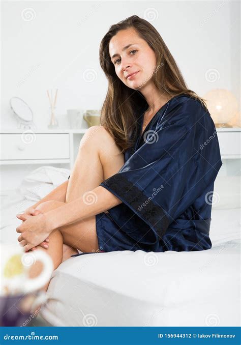 Seductive Woman In Blue Silk Robe Posing In Bed In Home Interior Stock