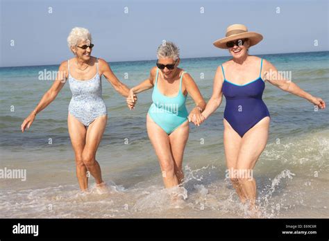 Senior Women Walking In Waves On Beach Stock Photo Alamy