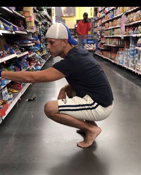 A Man Is Squatting Down In The Aisle Of A Grocery Store
