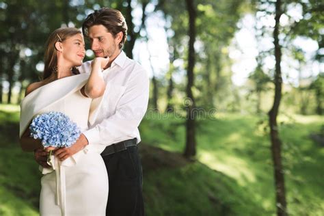 Affectionate Just Married Couple Embracing Standing Together In Forest
