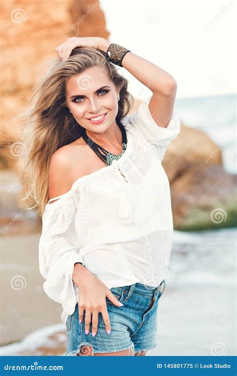 Pretty Blonde Girl With Long Hair Is Posing To The Camera On The Beach