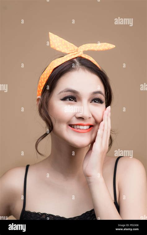 portrait of asian girl with pretty smile in pinup style touching face on yellow background stock